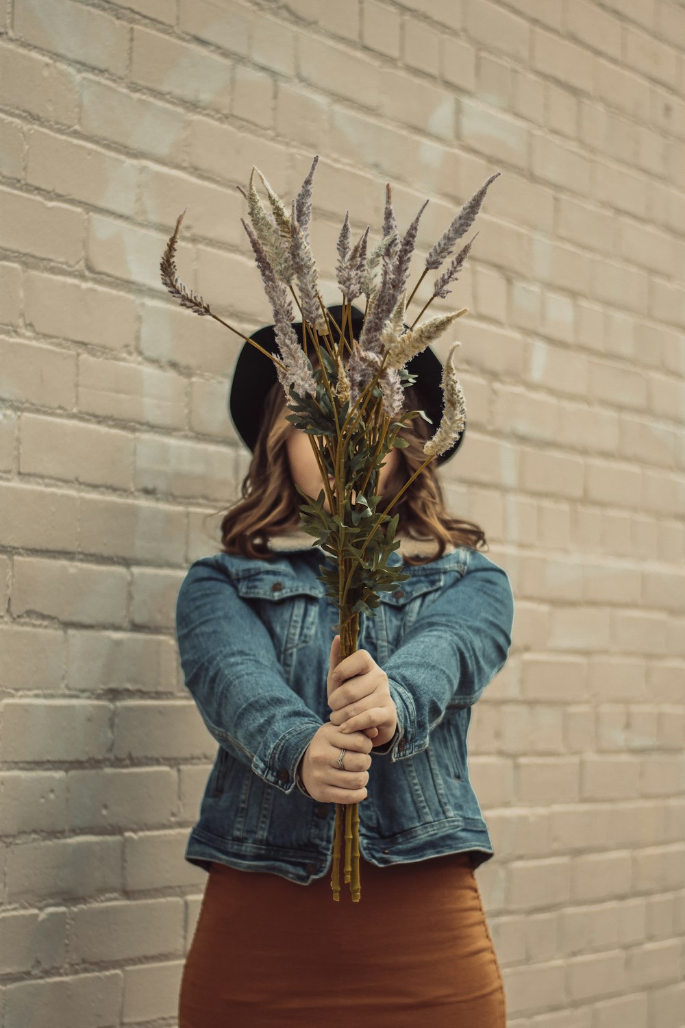 woman in blue denim jacket holding brown plant