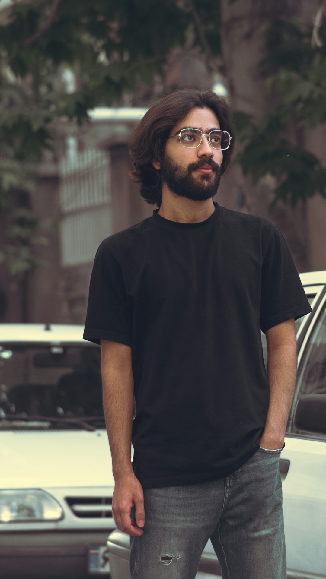 man in black crew neck t-shirt wearing black sunglasses standing near black car during daytime