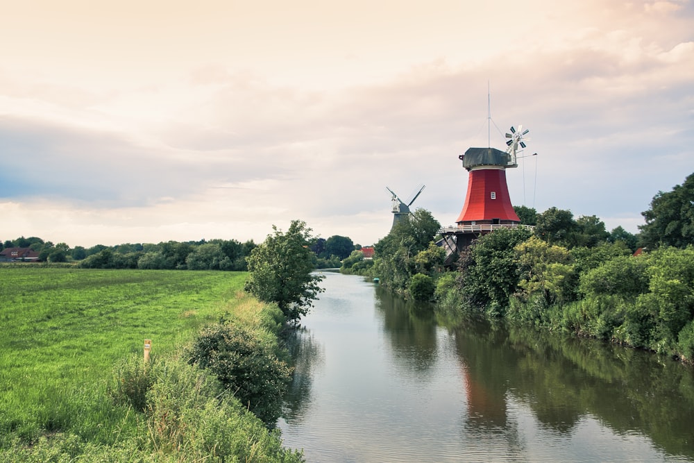 red and white lighthouse near green grass field and body of water during daytime