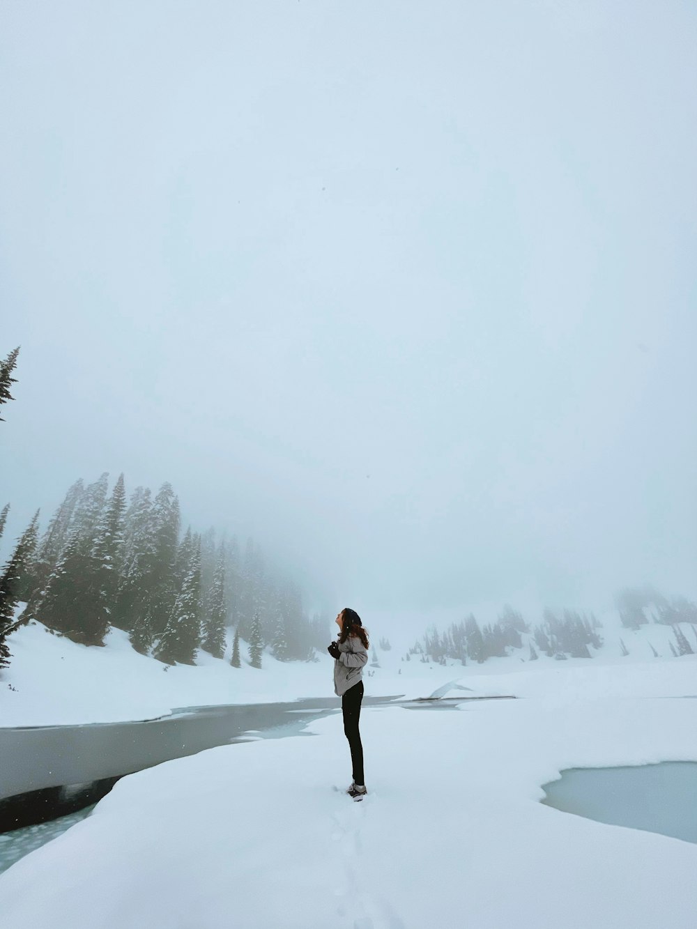 woman in white jacket and black pants standing on snow covered ground during daytime