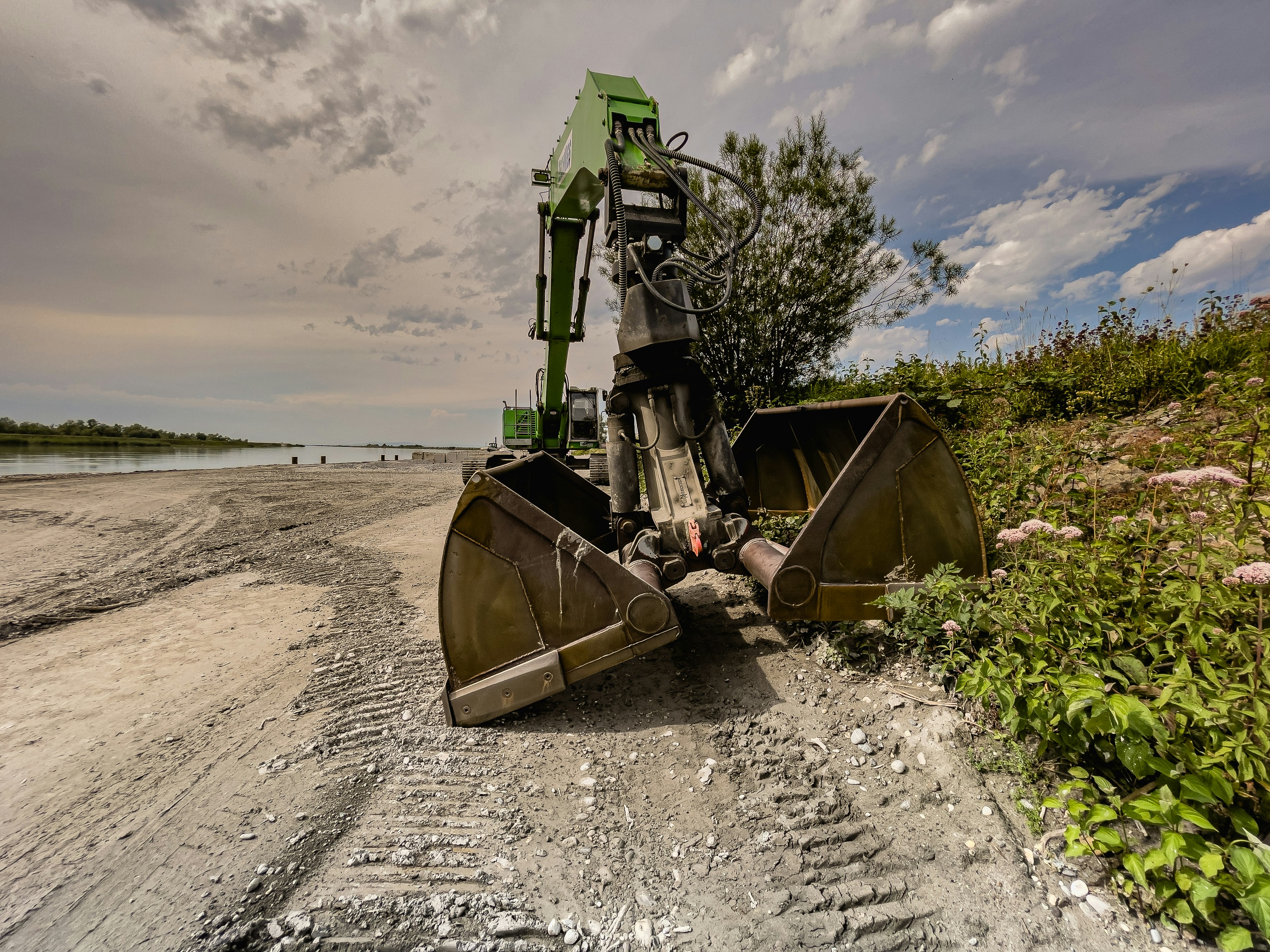 green and brown heavy equipment on gray sand under gray cloudy sky during daytime