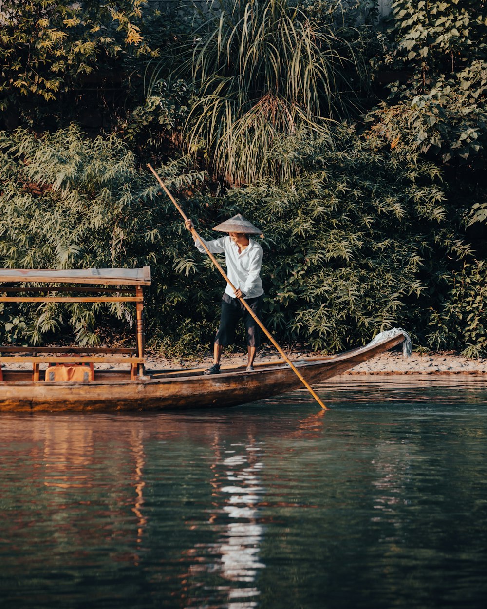 man in white shirt and blue denim jeans standing on brown wooden boat during daytime