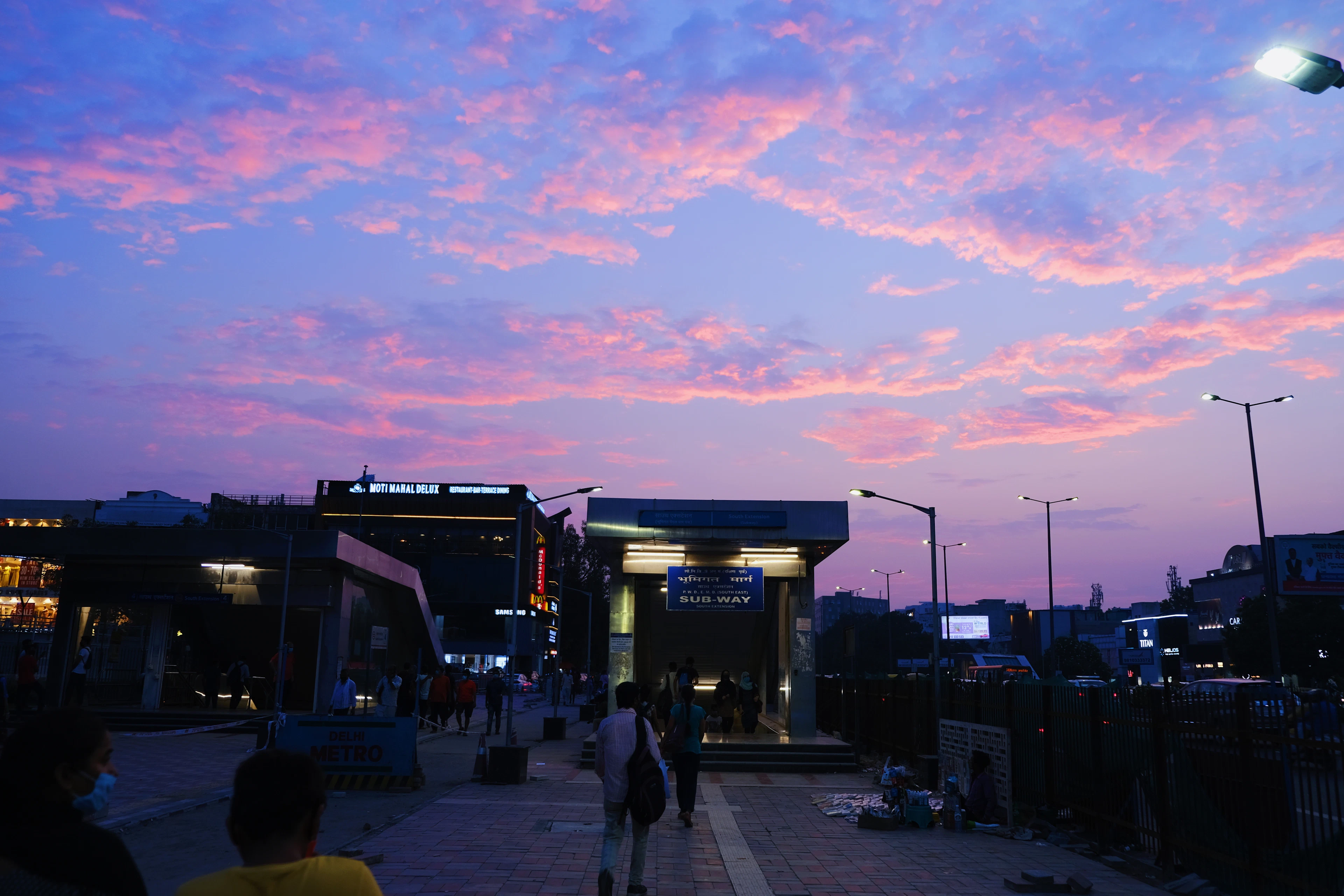 Metro station entrance at dusk under a pink sky