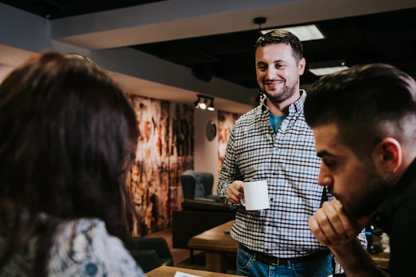 Close-up of smiling Asian alumni sharing stories over coffee in a modern lounge.