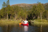 Couple enjoying a peaceful canoe ride on the calm waters of the Ceira river surrounded by lush greenery.