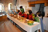 Públic assistint a una xerrada sobre cuina medieval en un ambient decorat amb estandarts i batalles històriques.