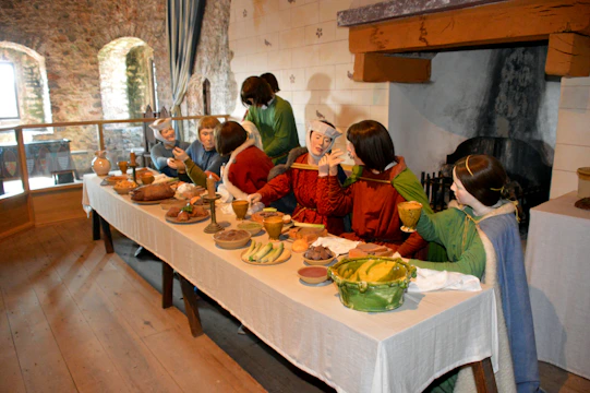 Públic assistint a una xerrada sobre cuina medieval en un ambient decorat amb estandarts i batalles històriques.
