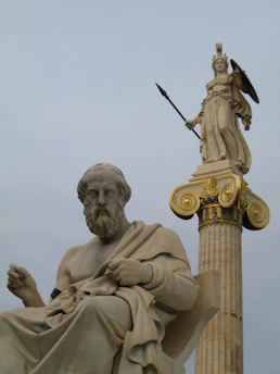 Elegant marble column with golden accents beside an open ancient philosophy book.