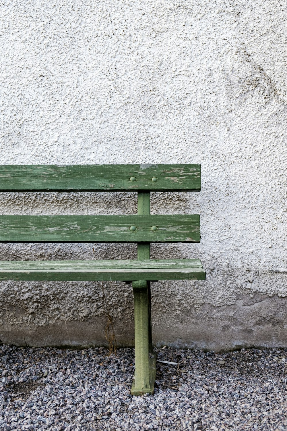 green wooden bench beside white wall