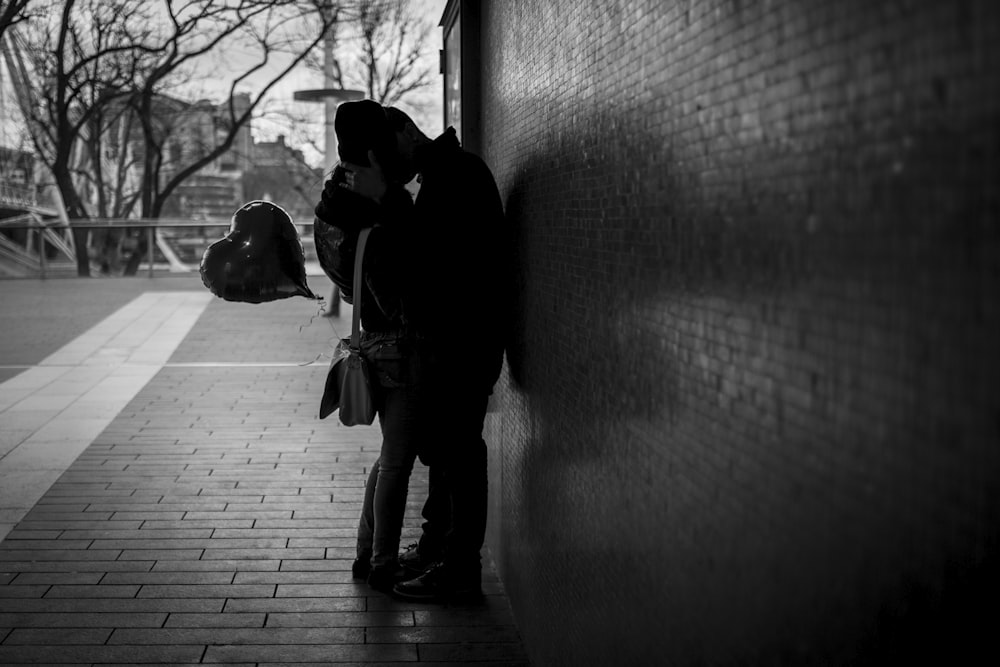 man in black jacket and pants standing beside wall