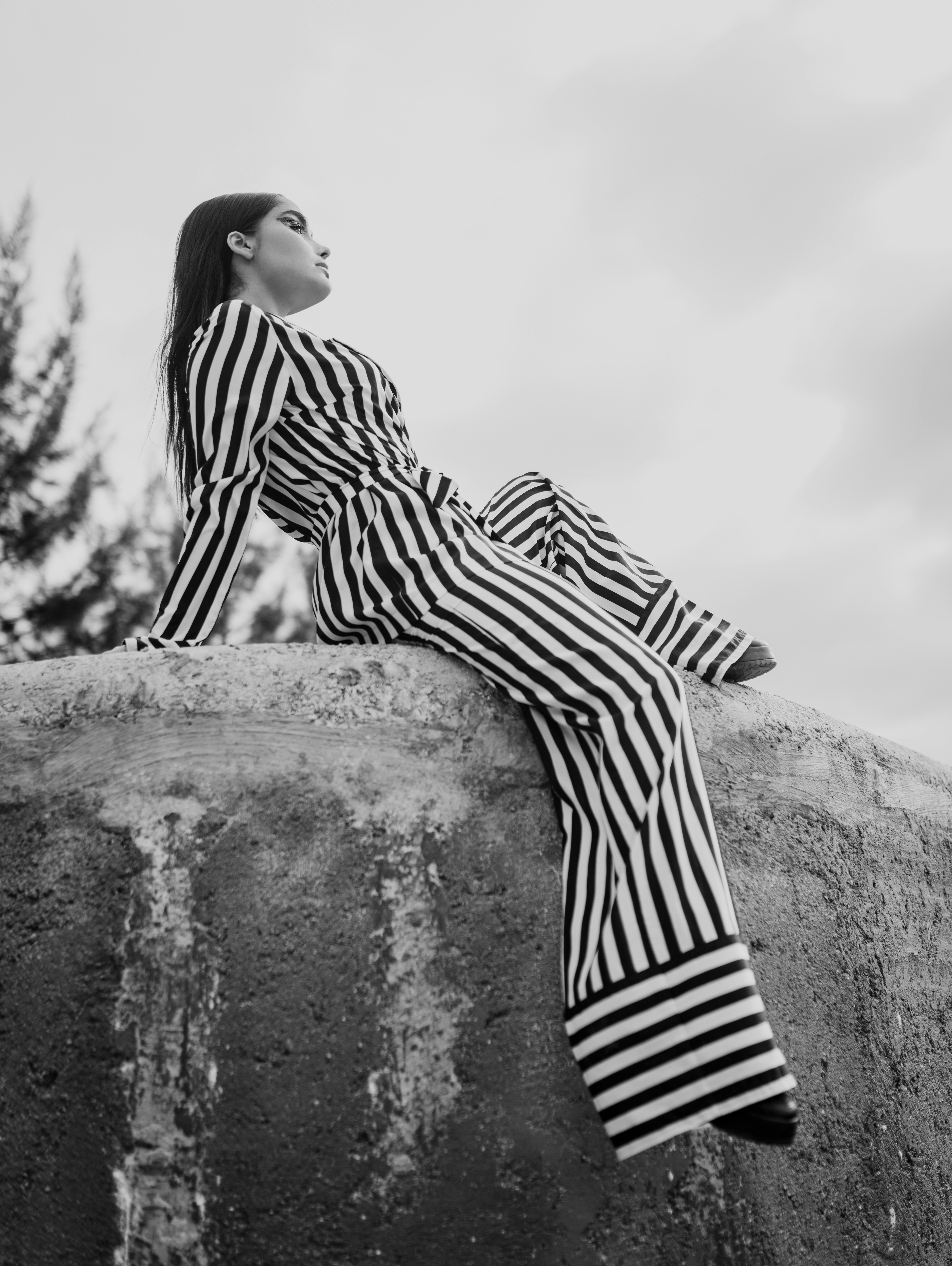 woman in black and white striped long sleeve dress sitting on rock