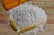 Close-up of a sack of wheat flour with a wooden scoop on a rustic kitchen table.