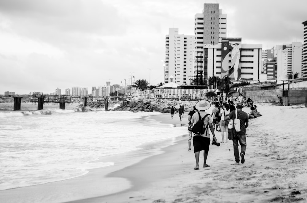 grayscale photo of people walking on beach