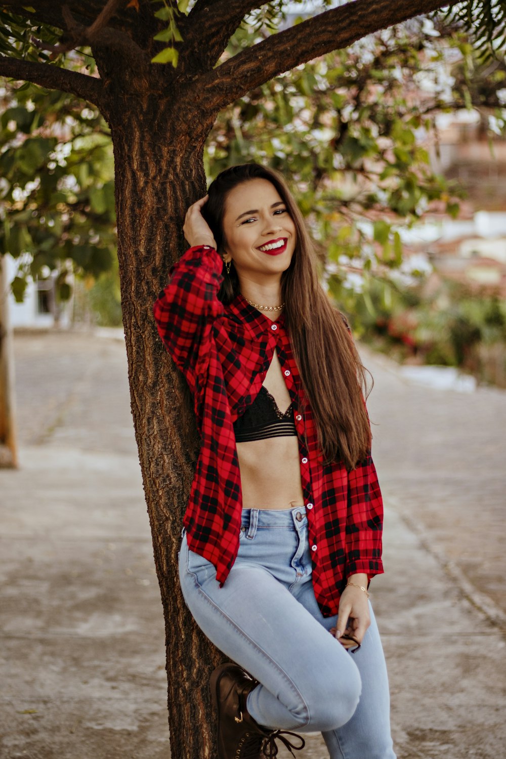 Woman in red and black checkered button up shirt and blue denim jeans  sitting on tree photo – Free Clothing Image on Unsplash