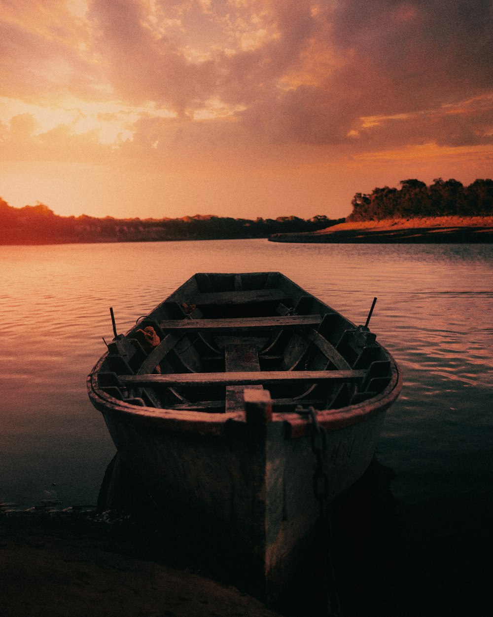 weißes und braunes Boot bei Sonnenuntergang auf dem Wasser