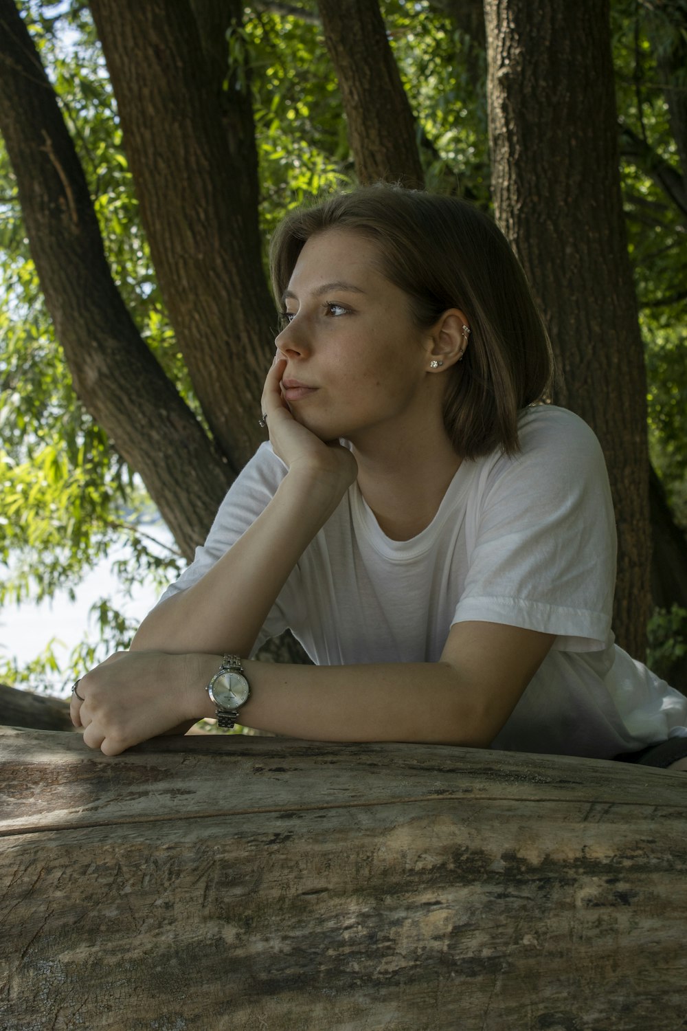 woman in white crew neck shirt sitting on brown wooden bench