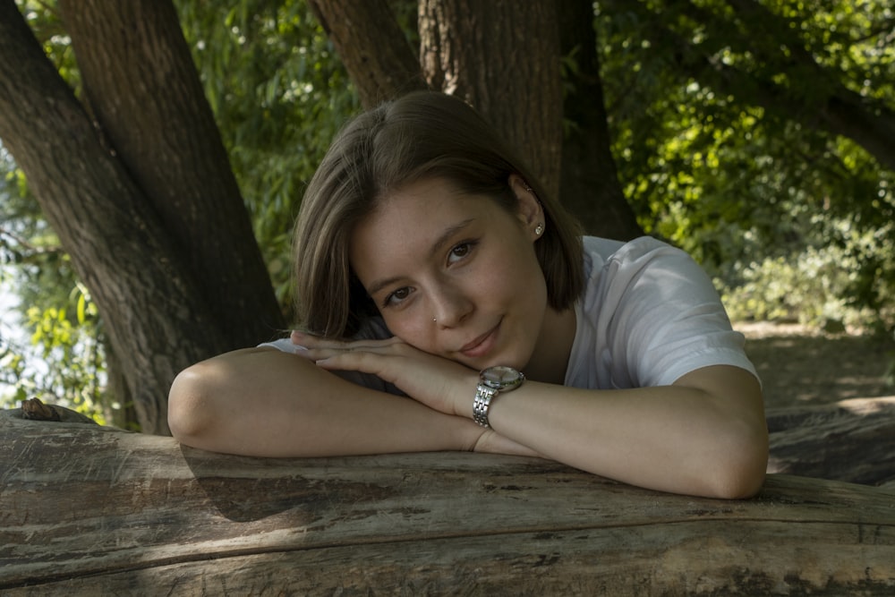 woman in white t-shirt leaning on brown wooden table