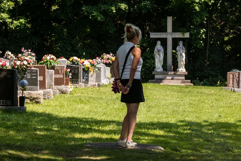 woman in black dress standing on green grass field during daytime