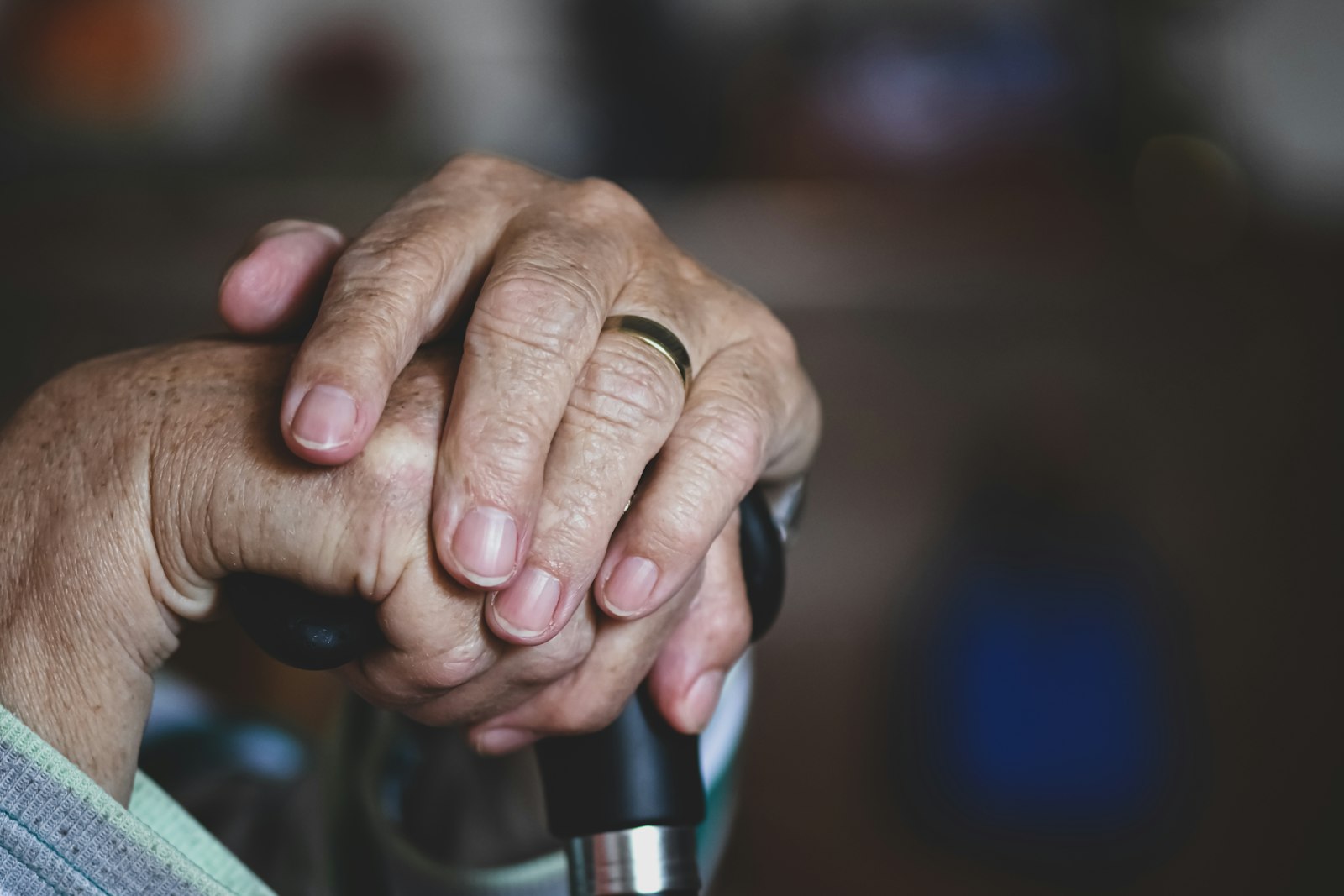 Older person's hand resting on walking cane