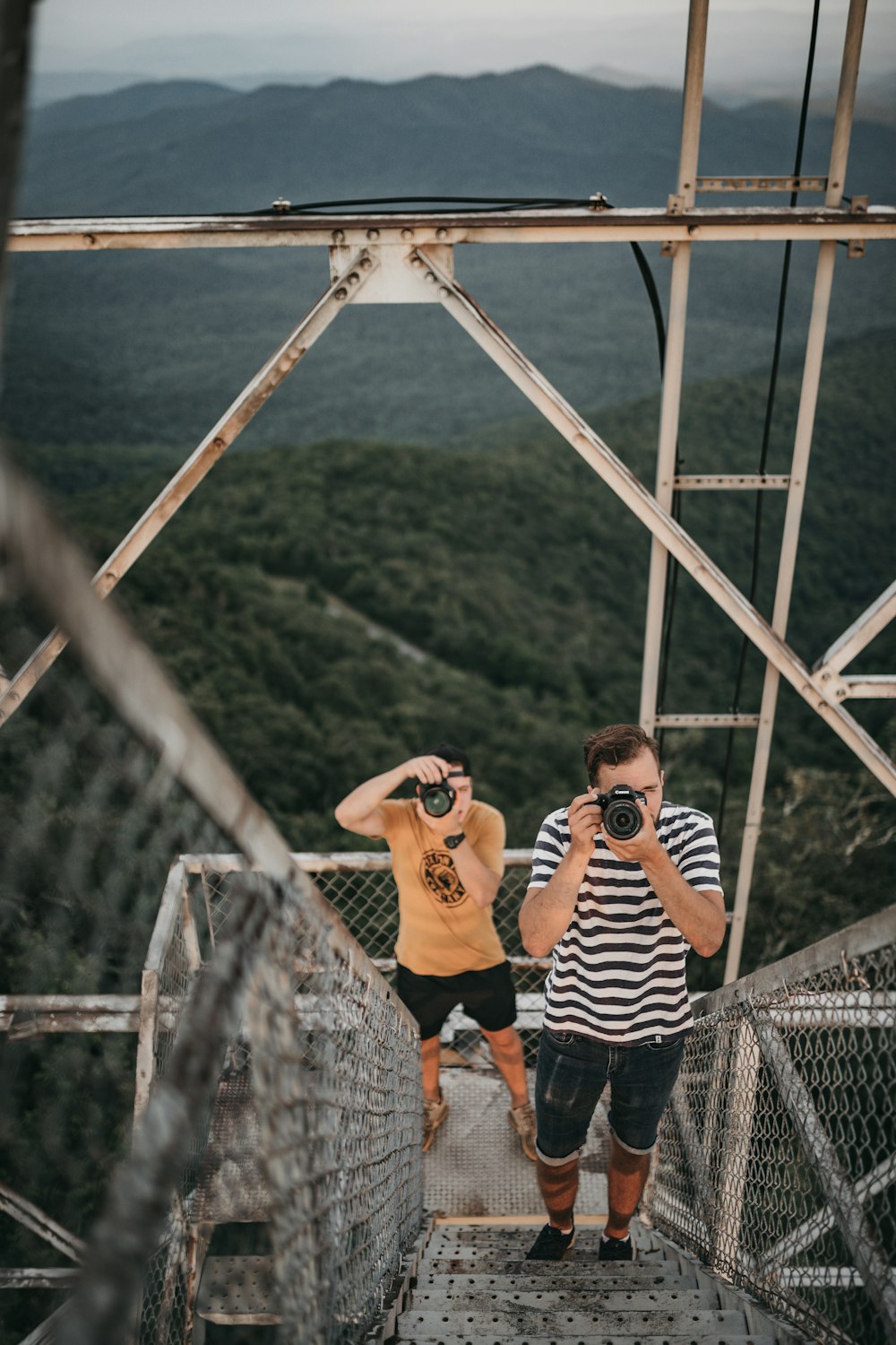 woman in black and white striped long sleeve shirt taking photo of mountain during daytime