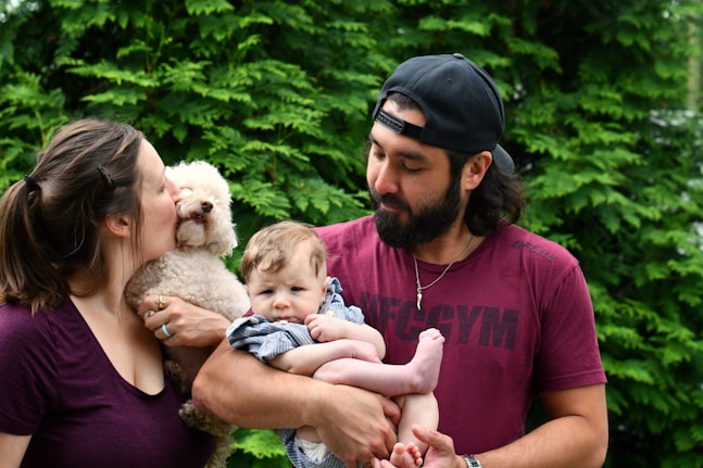 man in red crew neck t-shirt carrying baby in white and brown fur coat