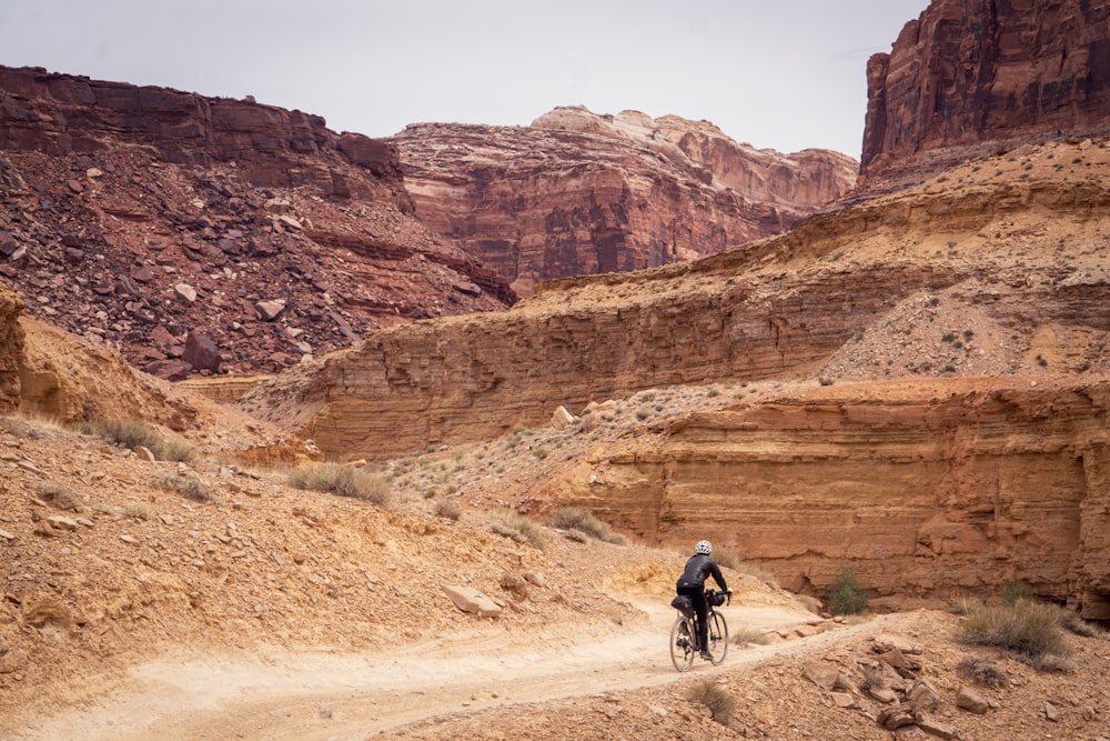 man in black jacket riding bicycle on brown dirt road during daytime