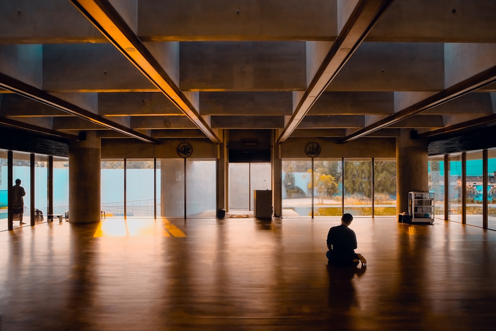 homme en veste noire assis sur un plancher en bois brun