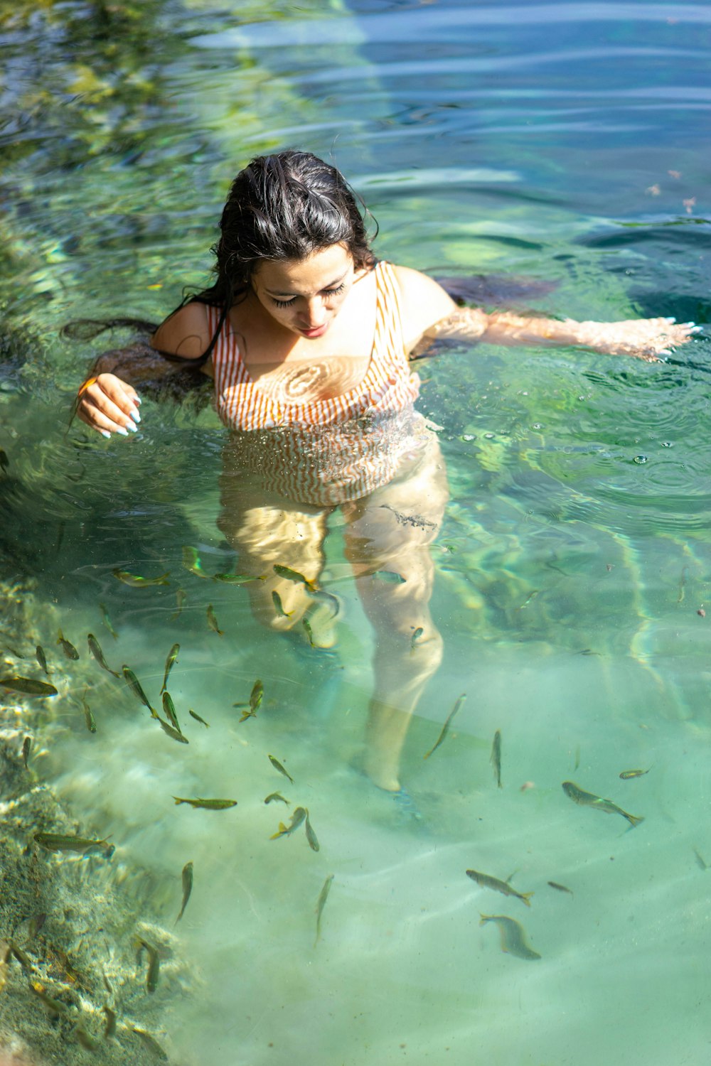 woman in brown and white polka dot bikini swimming on water