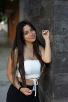 woman in white tank top leaning on wall