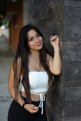 woman in white tank top leaning on wall