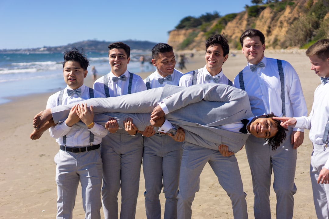 group of men in white dress shirt and brown pants standing on brown sand during daytime