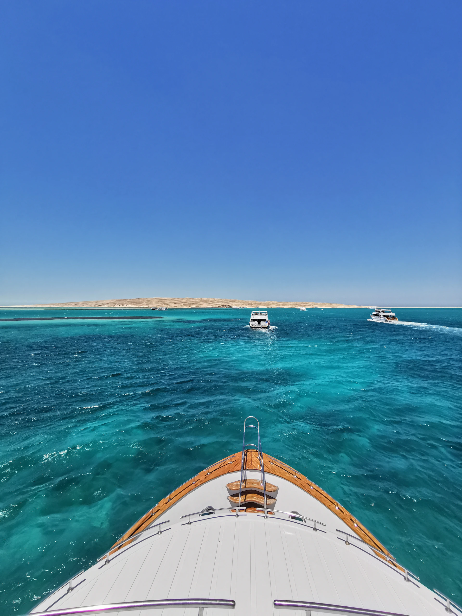 A vibrant boat cruising through crystal-clear turquoise waters with lush green islands in the background under a bright tropical sky.