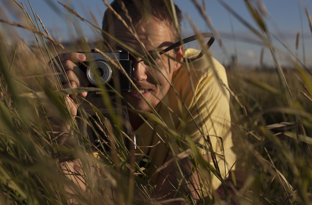 man in brown shirt holding black camera