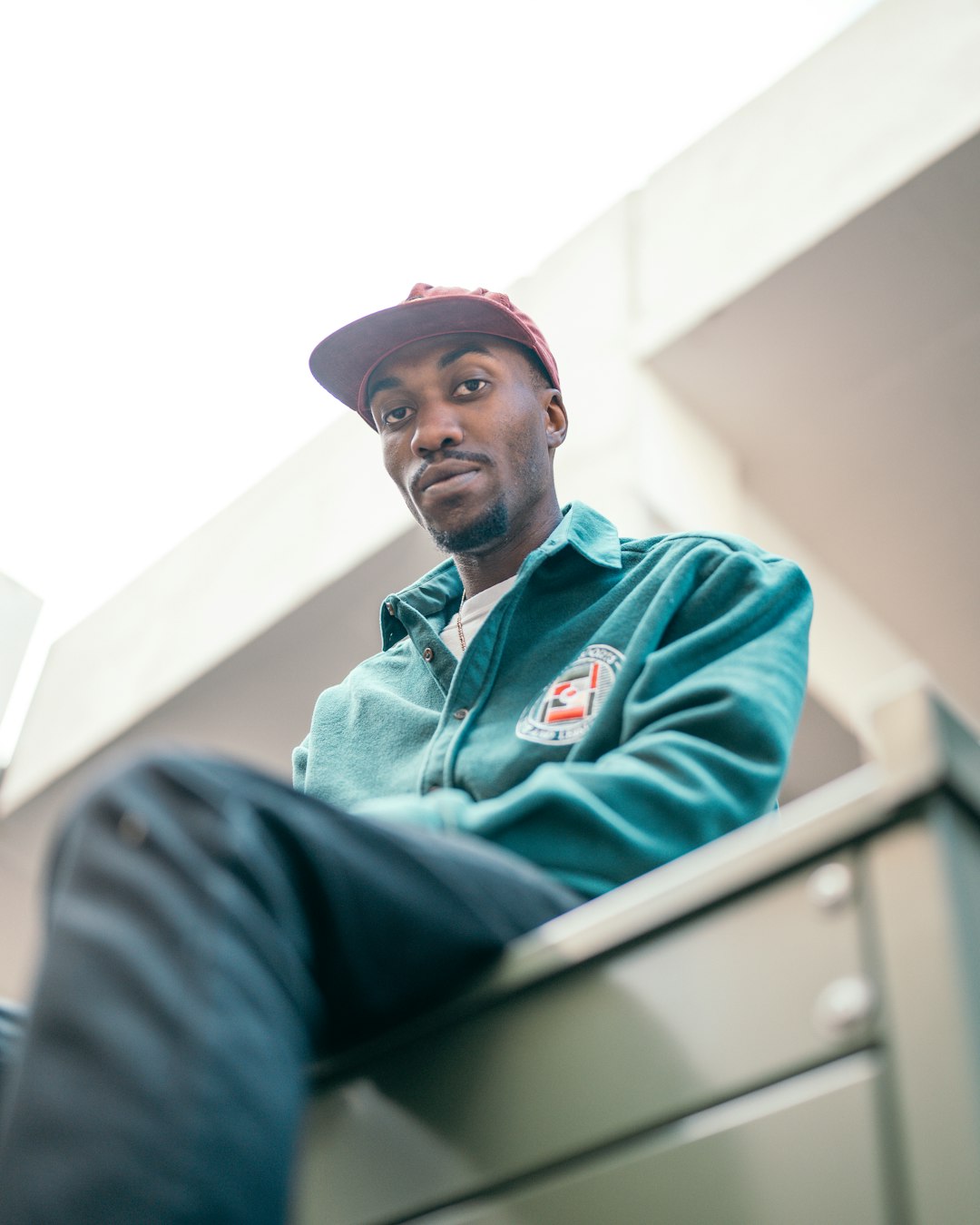 man in green hoodie sitting on white chair