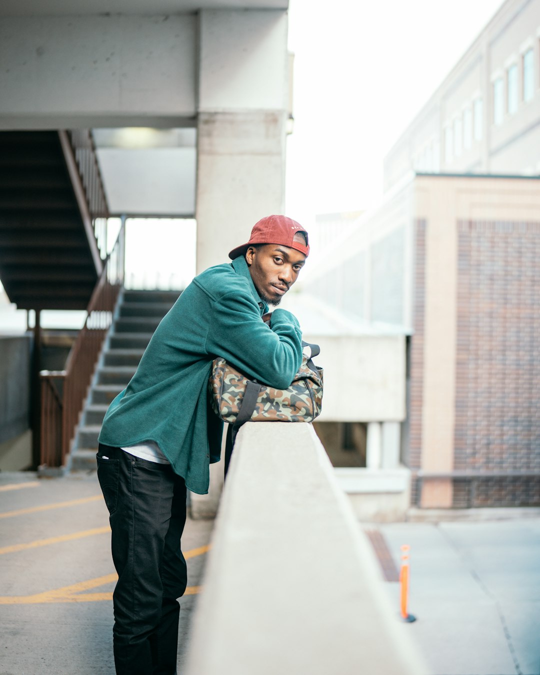 man in green hoodie and black pants standing on brown wooden floor