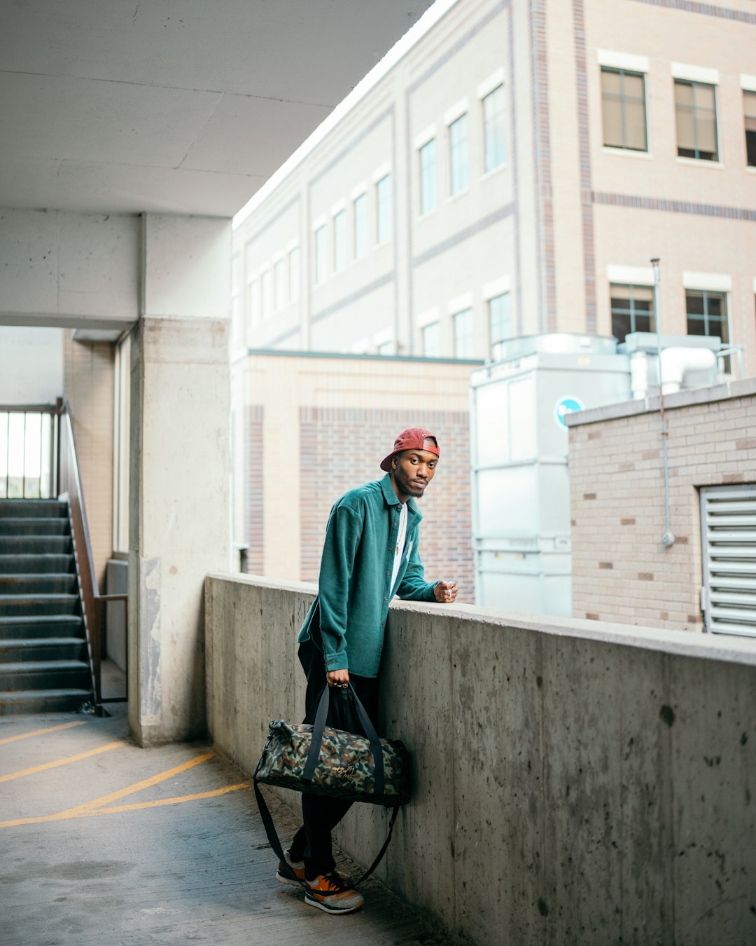 man in green jacket and black pants holding black skateboard