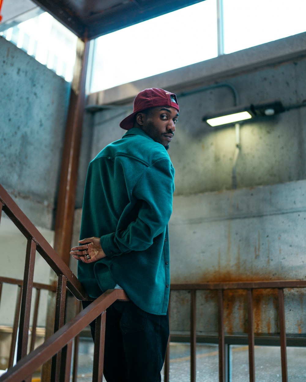 man in blue jacket standing beside brown wooden railings