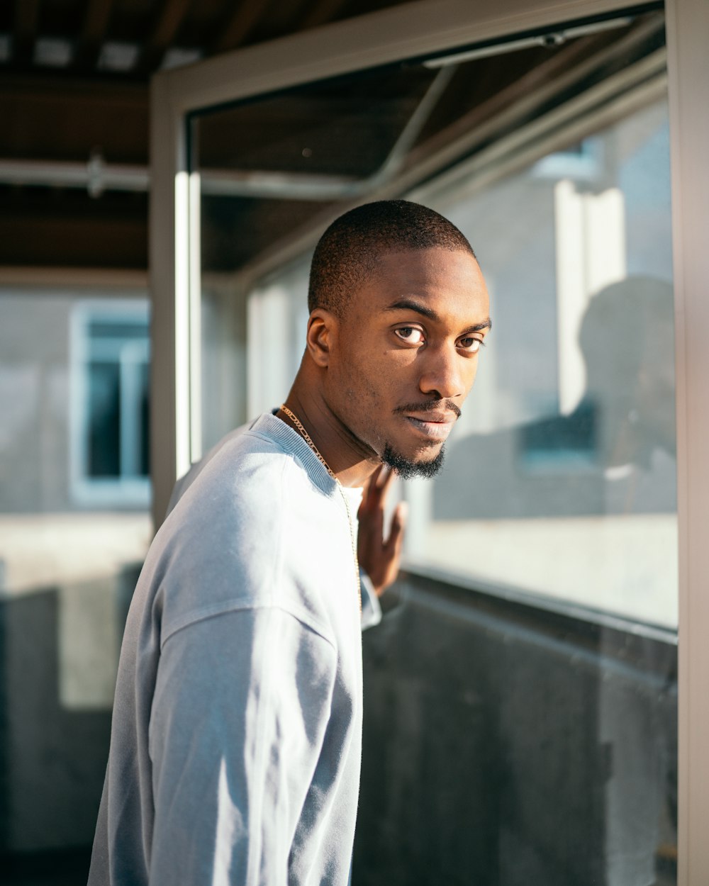 man in white dress shirt standing near glass window