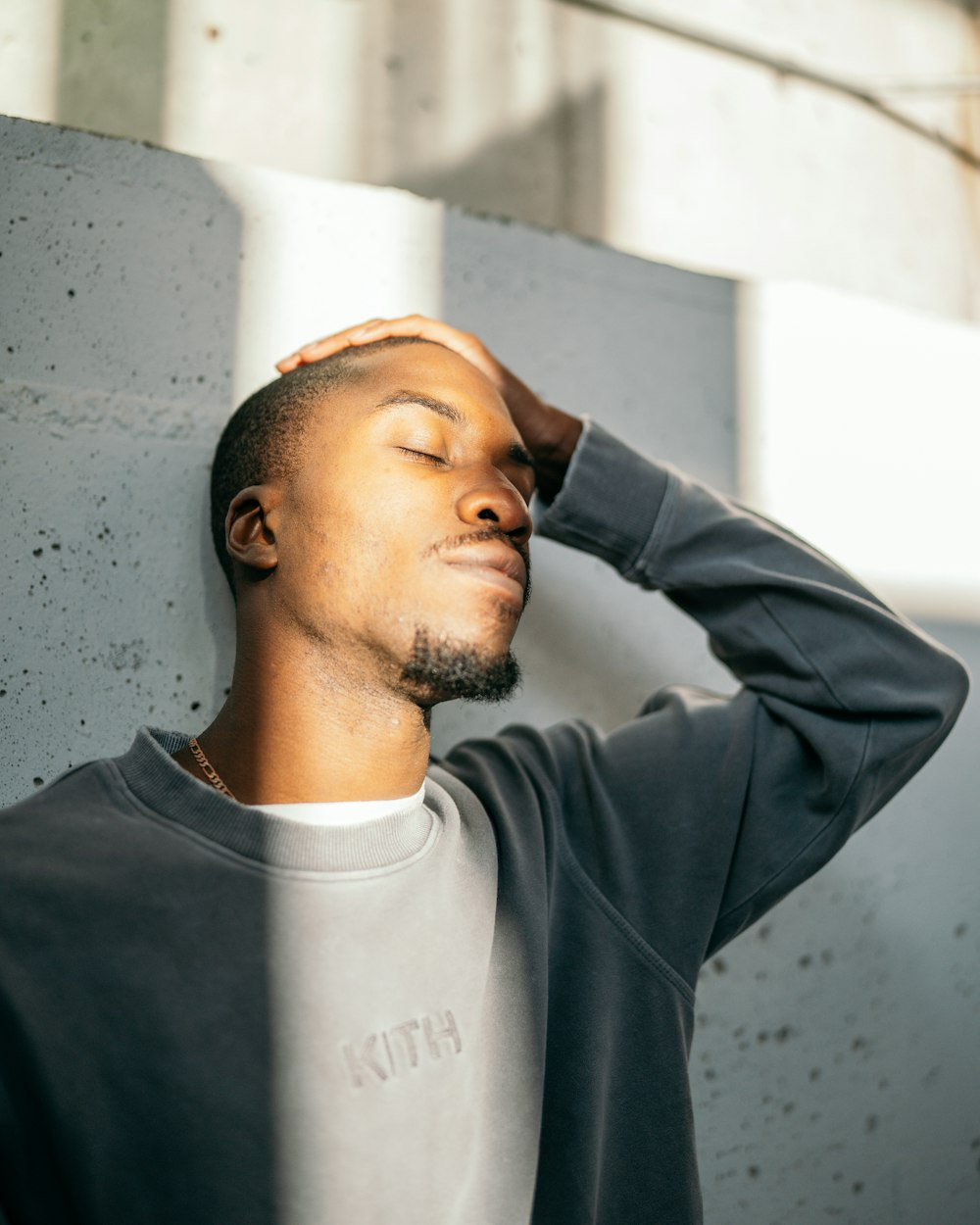 man in gray crew neck long sleeve shirt standing beside white wall