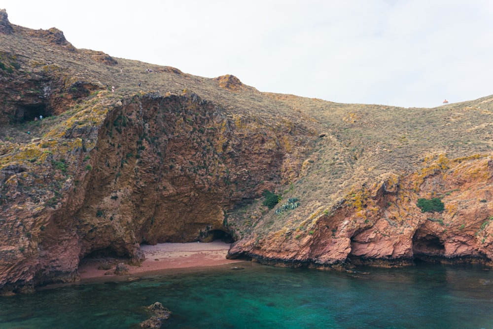 brown and green mountain beside body of water during daytime