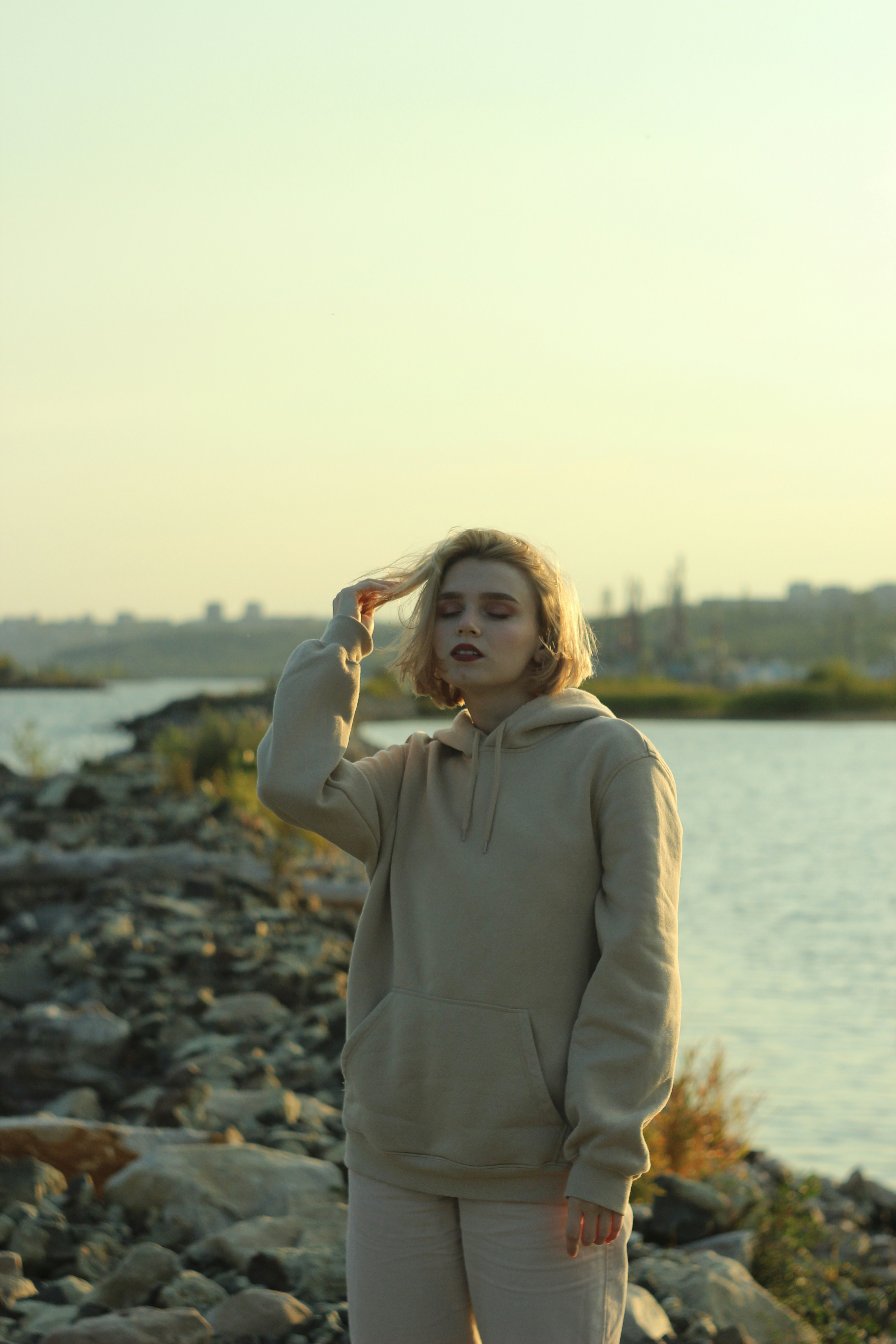 woman in gray long sleeve shirt standing on rocky shore during daytime