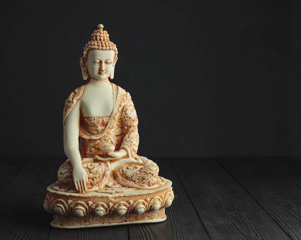 gold buddha figurine on brown wooden table