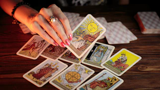 A serene woman sitting calmly with tarot cards spread softly in front of her, bathed in natural light.