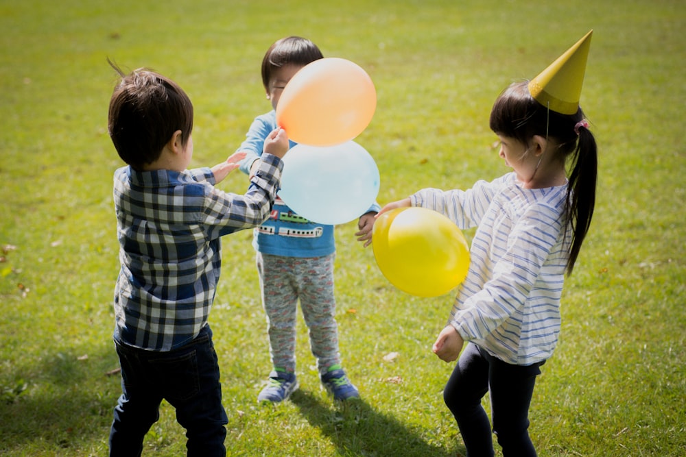 boy in blue and white plaid dress shirt holding yellow balloons