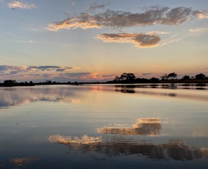 A scenic sunset over a quiet lake with reflections of colorful clouds.