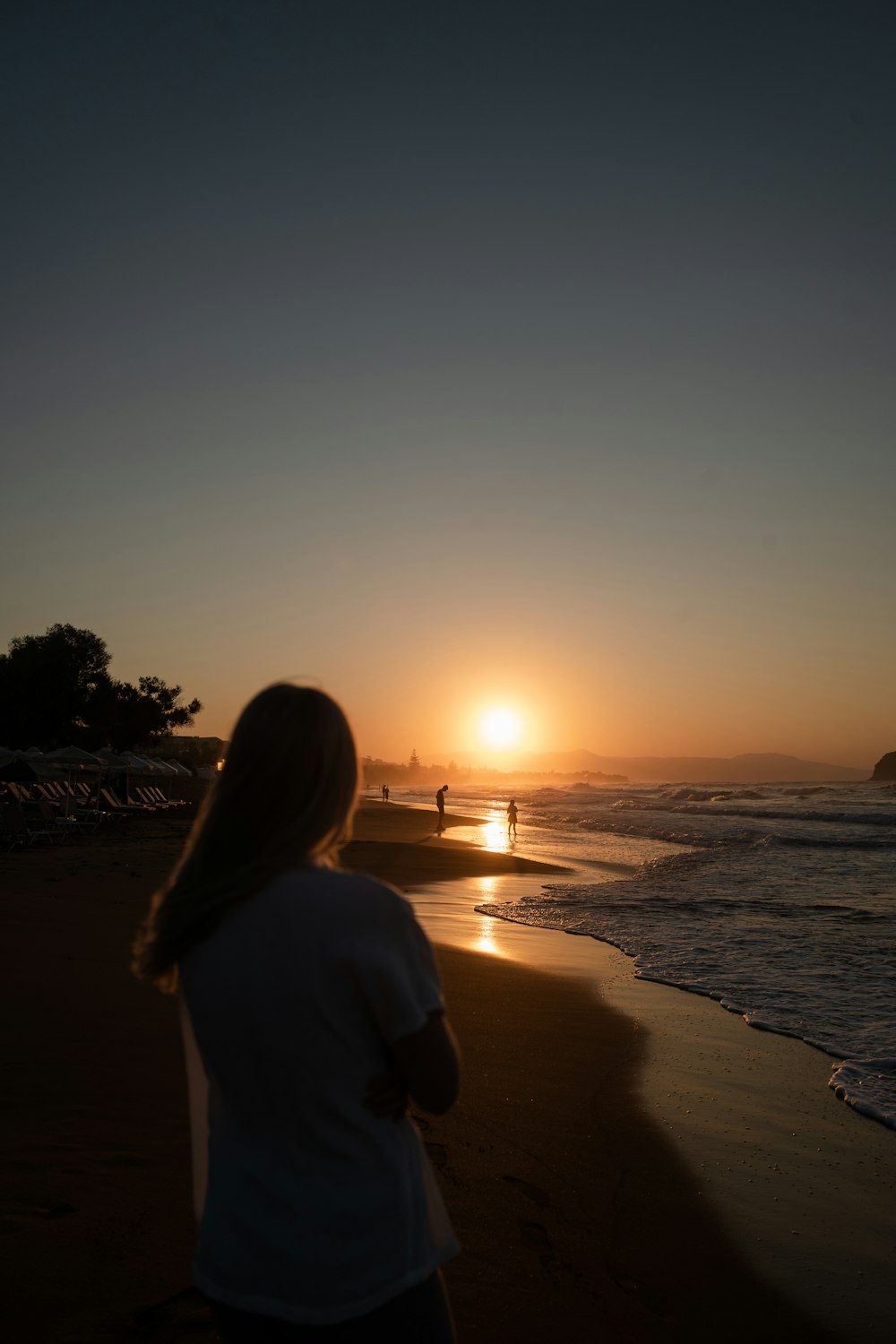 woman in white shirt standing on beach during sunset