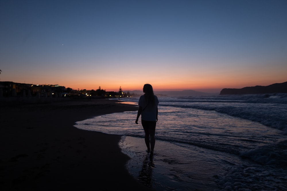 man in black jacket standing on beach during sunset