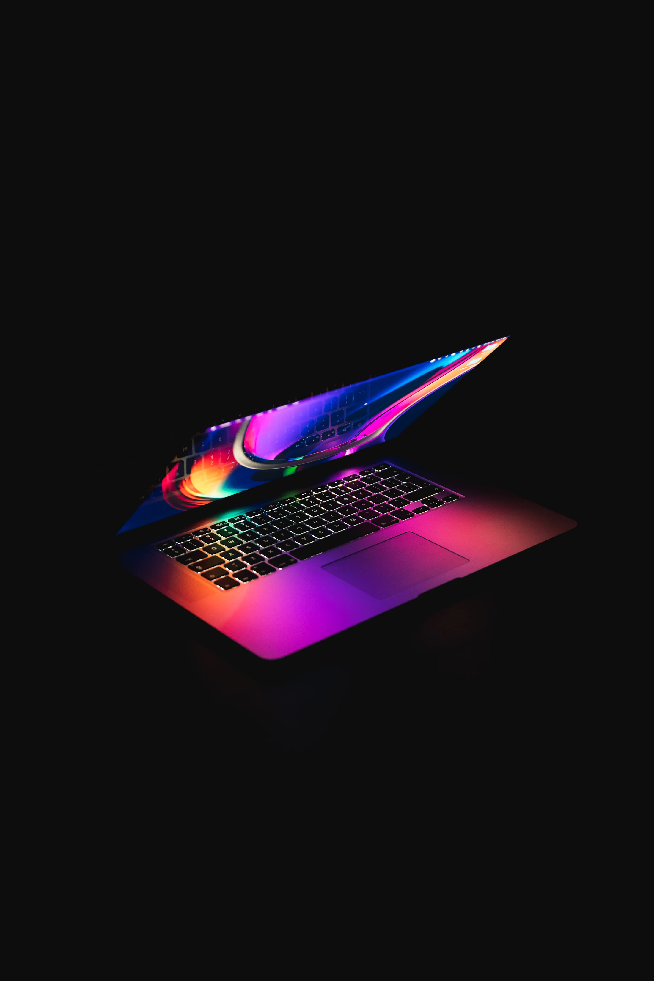 Portátil iluminado sobre fondo negro, visto como un objeto técnico