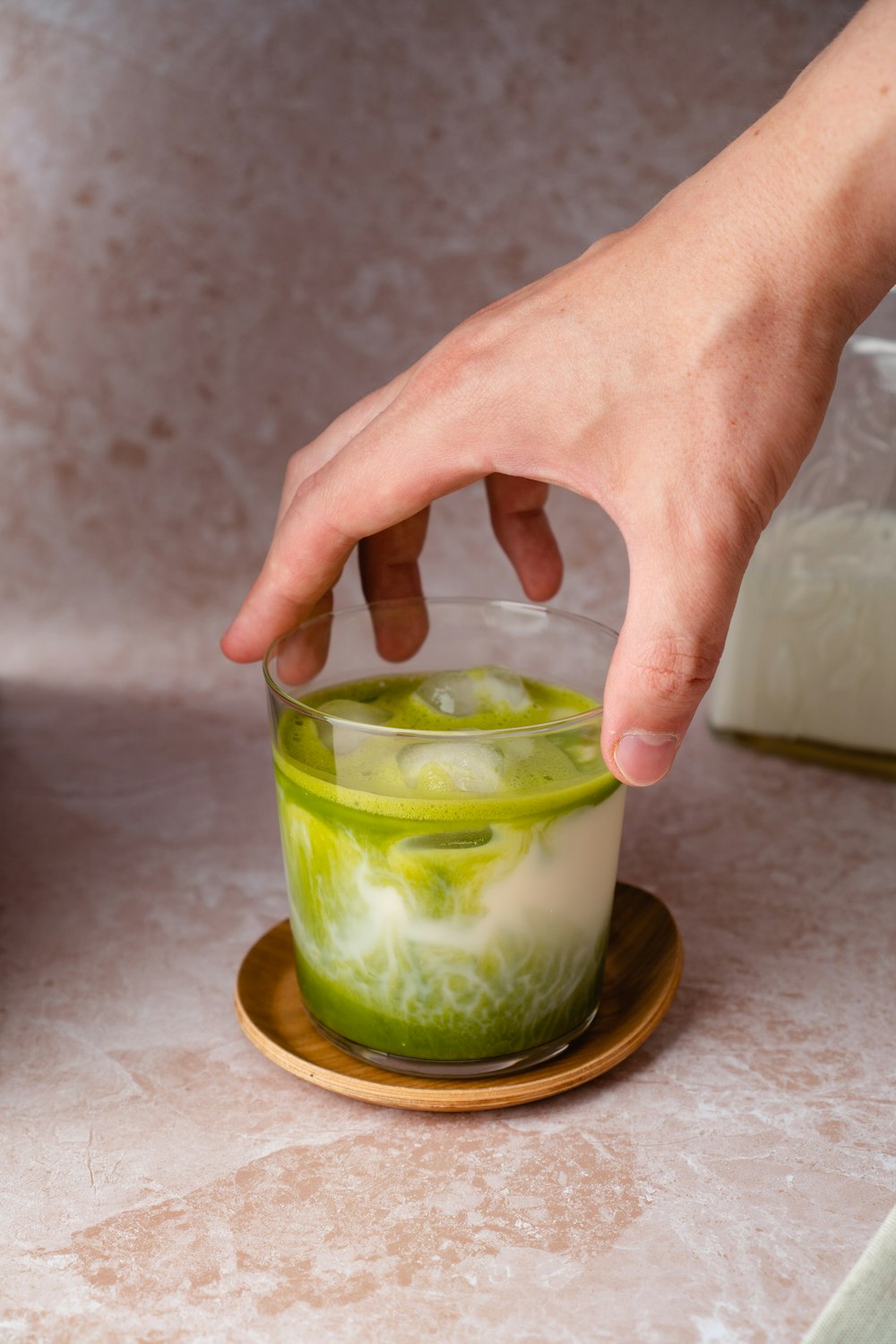 person holding clear drinking glass with green liquid