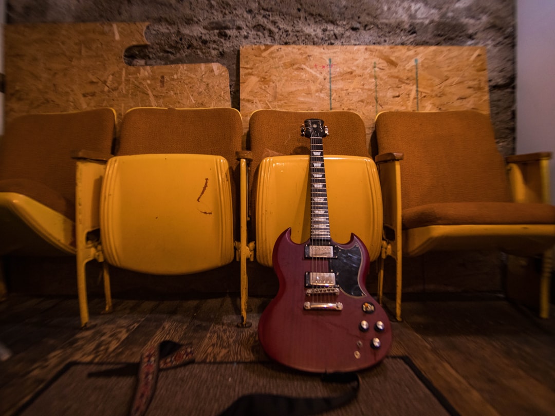 brown and black electric guitar on brown padded armchair